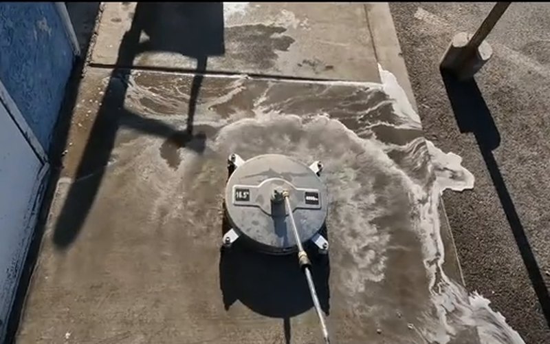 Surface cleaner and soap lifting grime off a church sidewalk in the sun